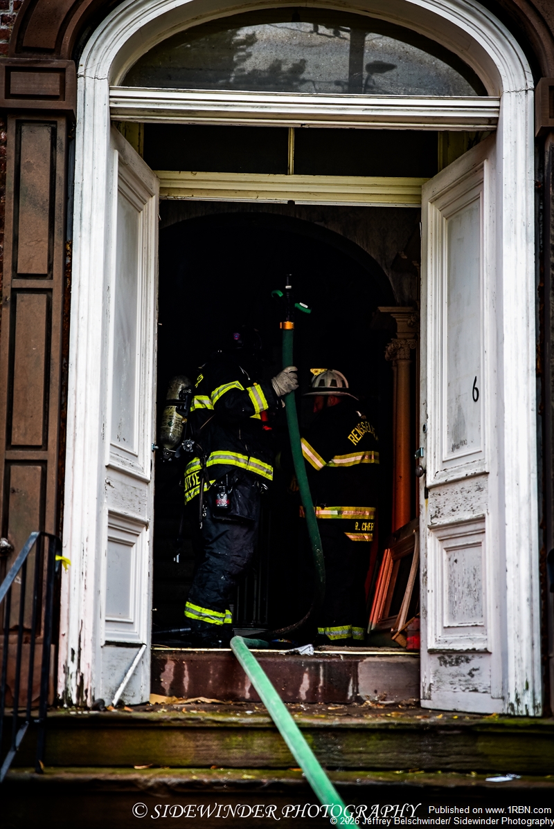 Firefighters pulling a hand line in to the house to hit hot spots