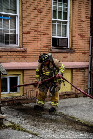 A Troy Firefighter Feeding A Hand Line In The Basement Window