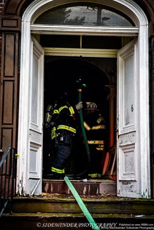 Firefighters pulling a hand line in to the house to hit hot spots