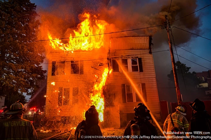 The Front facade of the building that was well involved collapses to the ground.