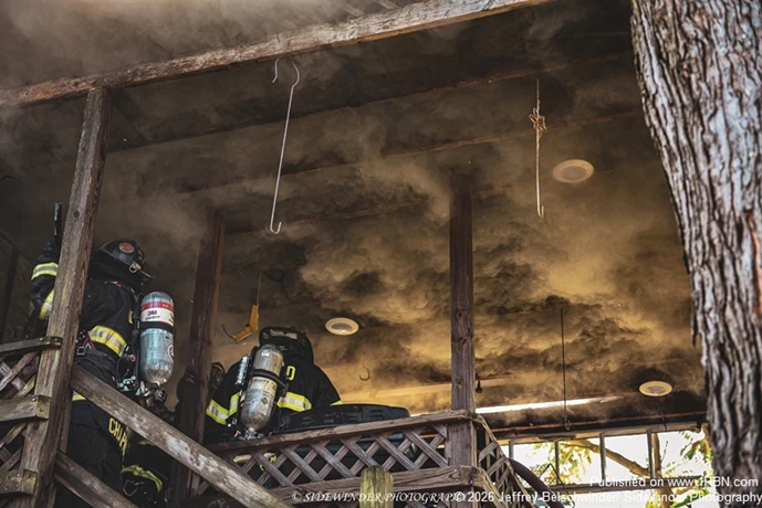 Heavy Smoke Rolls Across The Back Roof Area As Firefighters Push Into The Second Floor