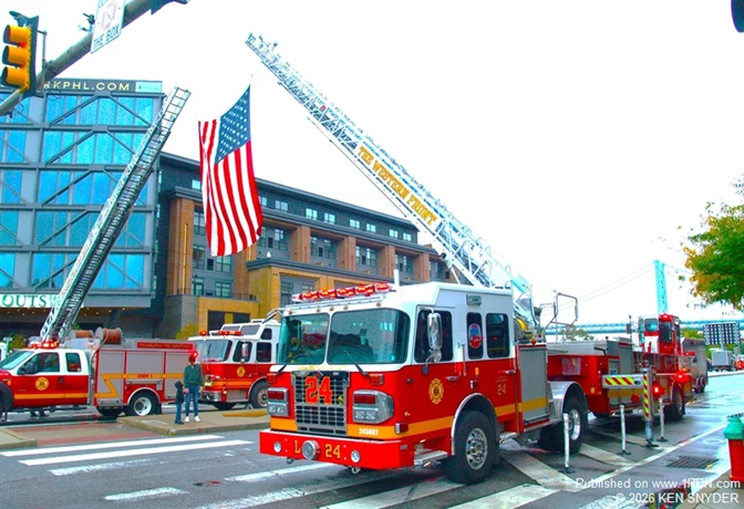 Philadelphia Fire Department Ladder 24 displays its aerial ladder alongside other apparatus, with an American flag suspended overhead during the 2026 Philadelphia Fire Muster.